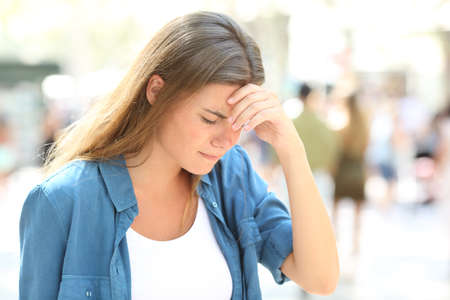 Painful girl suffering headache standing in the streetの写真素材