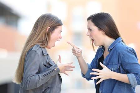 Two angry women fighting shouting each other in the middle of the streetの写真素材