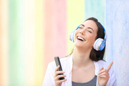 Happy girl singing listening to music with smart phone in a colorful streetの写真素材