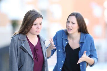 Angry woman scolding her guilty friend in the streetの写真素材
