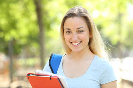 Happy teenage student posing looking at camera standing in a parkの写真素材