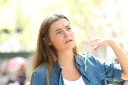 Unhappy woman fanning with the hand suffering heat stroke on summer in the street