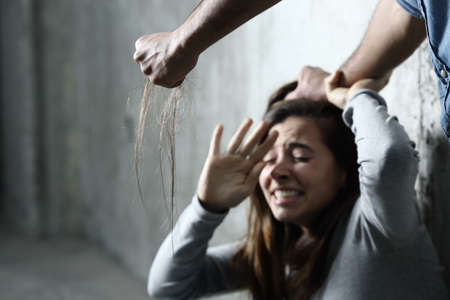 Scared abuse victim being attacked by a mad man in a dark placeの写真素材