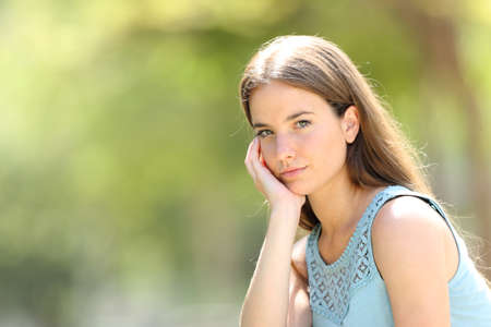 Portrait of a beauty serious woman looking at camera in a park  with a green backgroundの写真素材