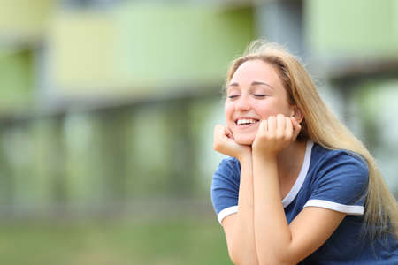 Happy teenage student relaxing meditating outdoors sititng in a campusの写真素材