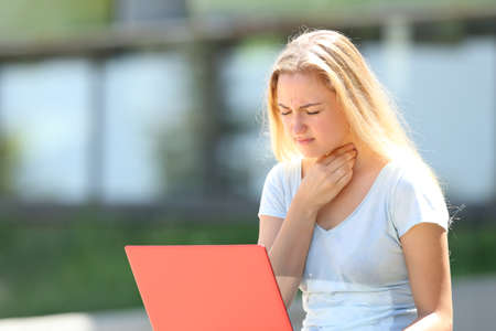 Student suffering throat ache outdoors in an university campusの写真素材