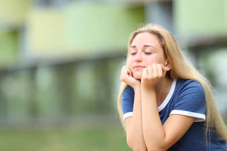 Relaxed teenage student meditating sitting outdoors in a campus