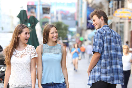 Happy man flirting with tho happy women walking in the streetの写真素材