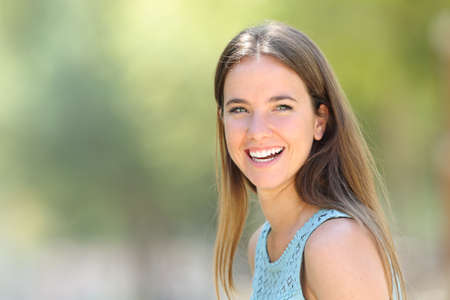 Portrait of a happy woman with perfect white smile looks away in a parkの写真素材