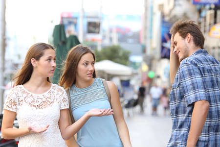 Man flirting being rejected by disappointed women walking in the streetの写真素材