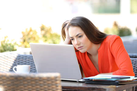 Frustrated entrepreneur working with a laptop sitting in a coffee shopの写真素材