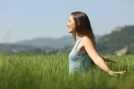 Side view portrait of a happy woman walking in a wheat fieldの写真素材