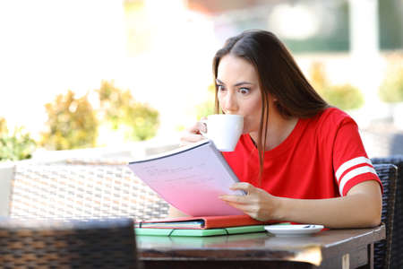 Overexcited student studying reading notes and drinking coffee in a bar terraceの写真素材