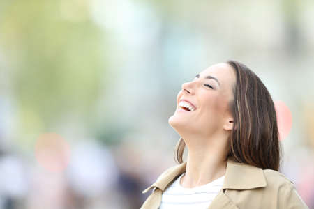 Happy woman breathing deeply fresh air standing in the streetの写真素材