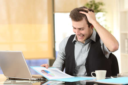 Excited businessman checking statistics on paper document at officeの写真素材