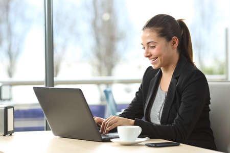 Happy businesswoman using a laptop sitting in a coffee shopの写真素材