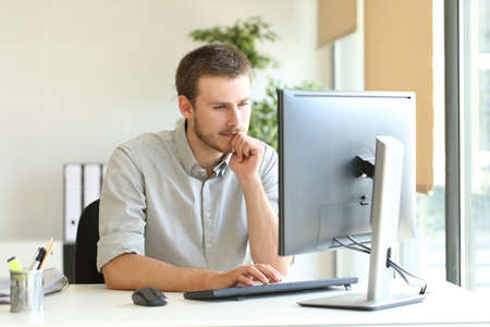 Concentrated businessman using computer watching online content at officeの写真素材