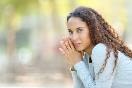 Serious beautiful mixed race woman posing looking at camera in a parkの写真素材