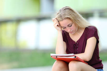 Serious student studying memorizing notes sitting outdoors in an university campusの写真素材