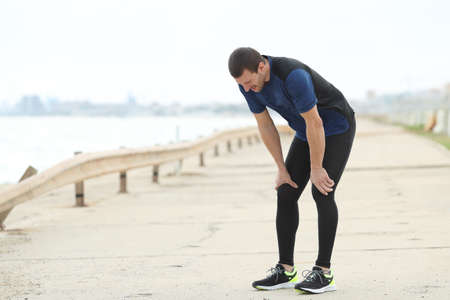 Exhausted runner resting breathing fresh air after sportの写真素材