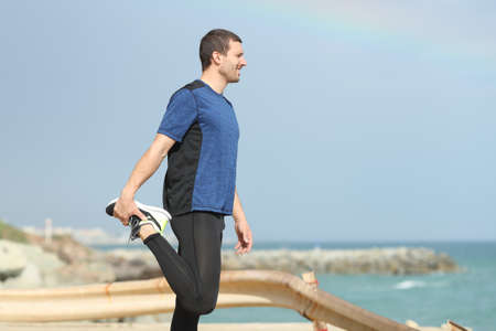 Side view of a runner stretching legs looking at sea on the beachの写真素材