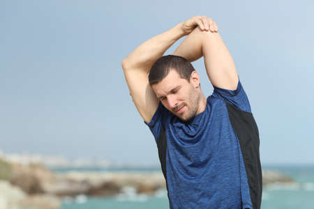 Hansome runner stretching after sport on the beachの写真素材