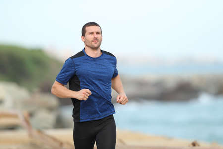 Serious runner running working out alone on the beachの写真素材