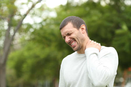Man suffering neck ache complaining standing alone in a parkの写真素材