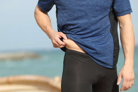 Close up of a sportsman hand pinching body fat outdoors on the beachの写真素材