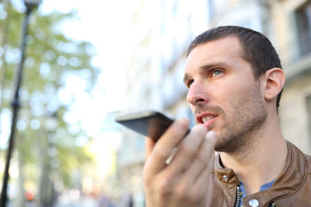 Adult man using voice recognition on mobile phone to send a recorded message in the streetの写真素材