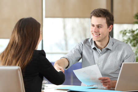 Happy businessman and woman handshaking after successful deal at officeの写真素材