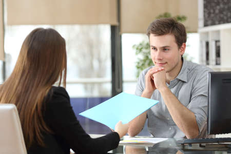 Two attentive businesspeople talking and sharing report at officeの写真素材