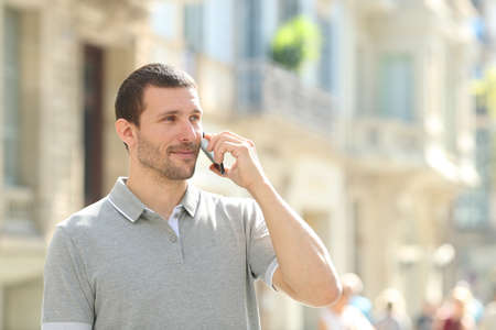 Serious adult man talking on smart phone standing in the streetの写真素材