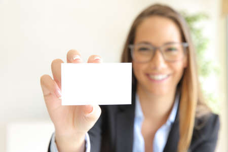 Front view of a happy businesswoman showing blank card at officeの写真素材