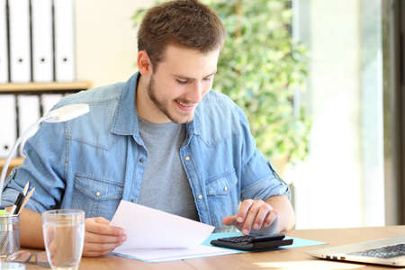 Happy entrepreneur calculating using a calculator sitting on a chair working at officeの写真素材