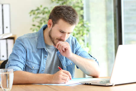 Pensive entrepreneur handwriting using pen sitting on a chair at officeの写真素材