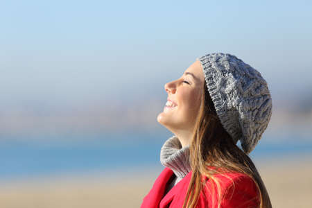 Happy woman breathing deeply fresh air celebrating new day standing on the beach in winterの写真素材