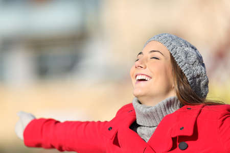 Happy satisfied woman breathing fresh air celebrating new day outstretching arms in winterの写真素材