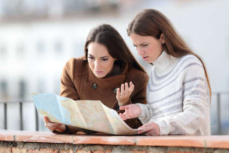 Lost tourists checking paper map in a balcony on winter holidaysの写真素材
