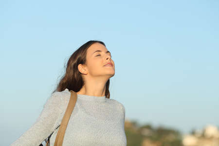 Relaxed woman breathing fresh air with a blue sky in the backgroundの写真素材