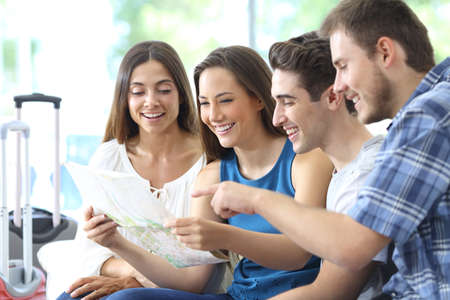 Group of tourists planning vacation checking maps sitting on a couch in the living room at homeの写真素材
