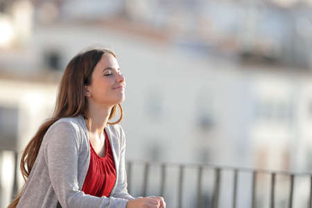 Relaxed woman breathing deeply fresh air in a balcony a sunny dayの写真素材