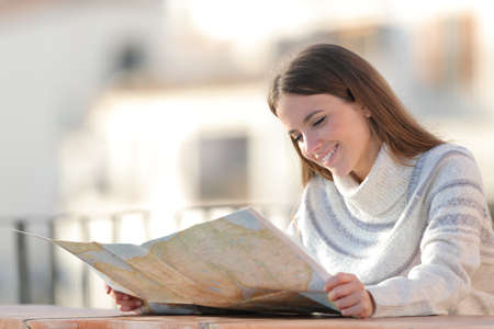 Happy tourist checking a paper map on winter vacation in a balconyの写真素材