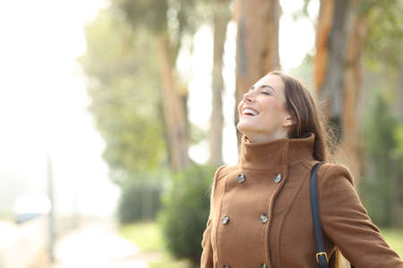 Happy woman breathing deeply fresh air standing in a foggy park in winterの写真素材