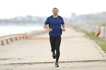 Runner training running towards camera on a concrete wayの写真素材