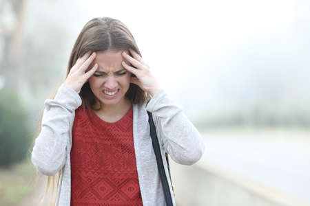 Front view portrait of an woman complaining suffering migraine a foggy dayの写真素材