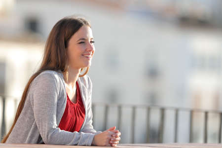 Happy woman contemplating views in a balcony a sunny dayの写真素材
