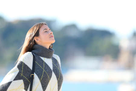Relaxed woman wearing jersey breathing deeply fresh air on the beach in winterの写真素材