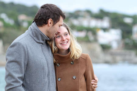 Happy couple in love flirting walking together on the beach in winterの写真素材