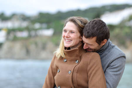 Happy couple in love flirting and laughing on the beach in winterの写真素材